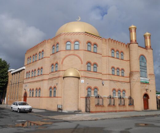 Al-Rahma Mosque on Hatherley Street, Toxteth, Liverpool: a sandy-brick building with arched windows, a large gold dome topped with a crescent and two gold-capped minarets