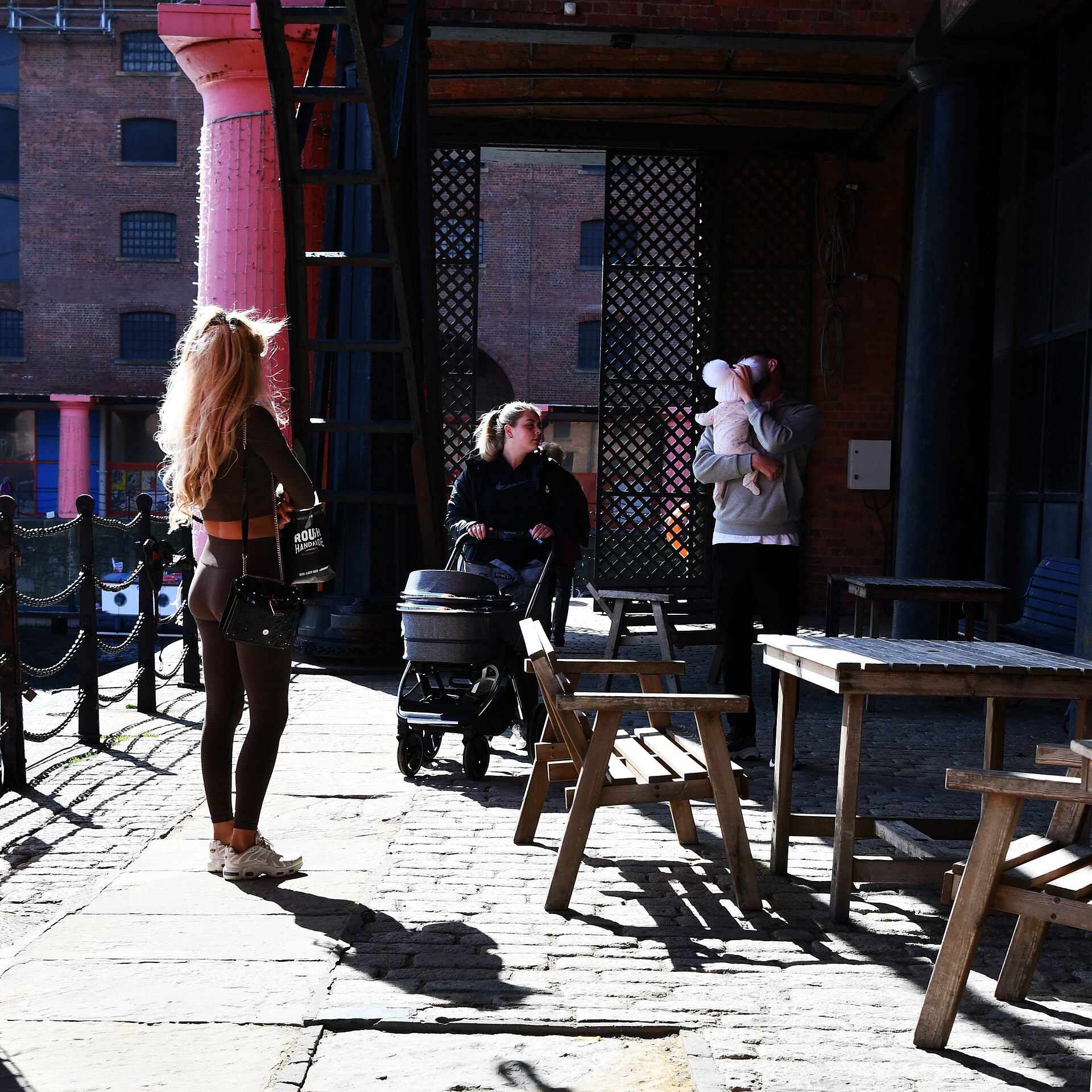 A pushchair being wheeled along the smooth paving strip that runs between the cobbles on the Albert Dock walkway in Liverpool