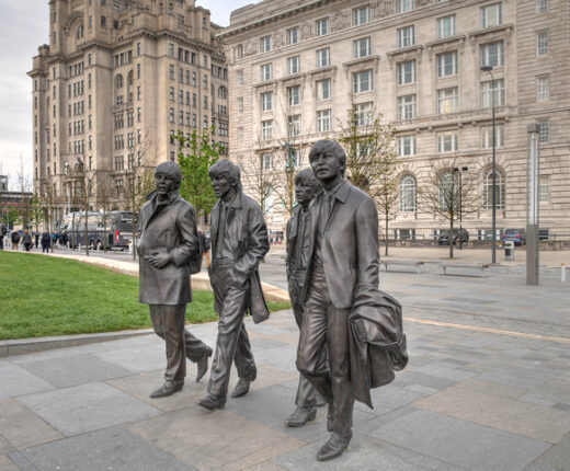 The bronze Beatles statue at the Pier Head in Liverpool, with the Royal Liver Building and Cunard Building behind