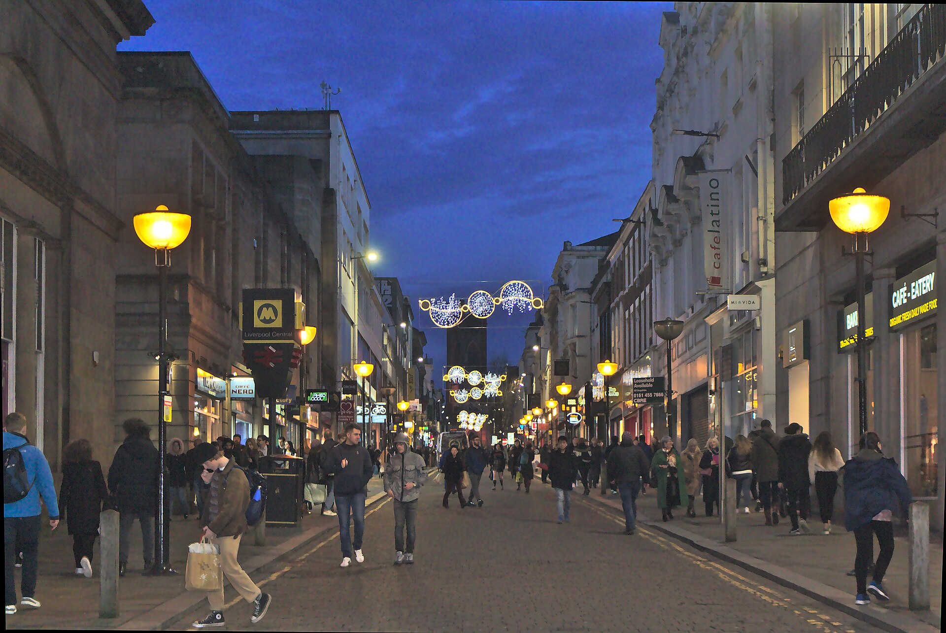 Competitive Socialising in Liverpool: Crazy Golf, Darts & Escape Rooms 2 Bold Street in Liverpool at dusk, busy with shoppers, with glowing street lamps, Christmas lights strung across the road and the tower of St Luke's church at the far end