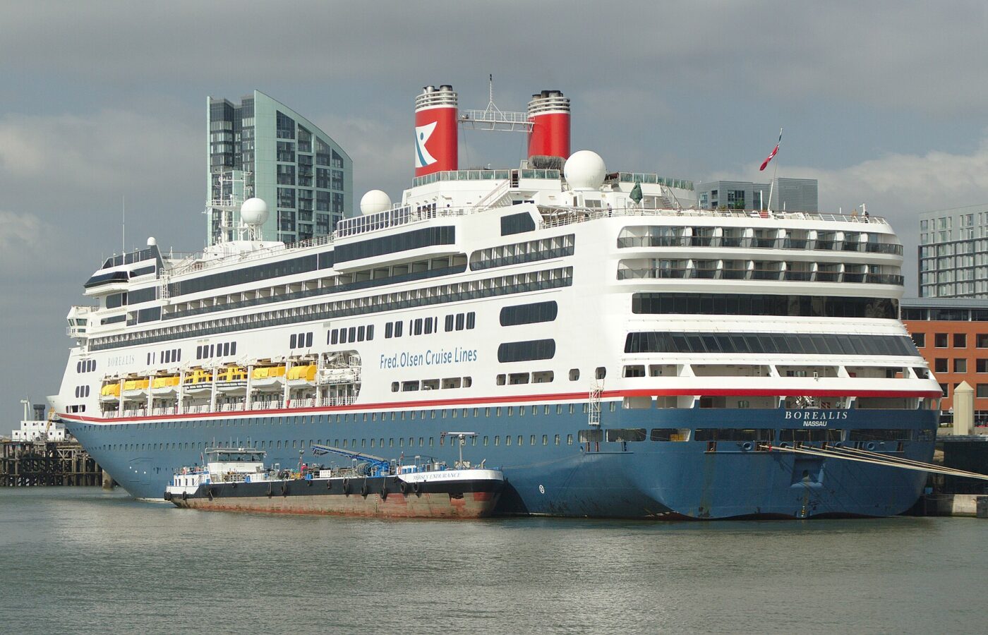 Liverpool Cruise Terminal Guide: Arrivals, Transfers & Facilities 4 The Fred. Olsen cruise ship Borealis moored at Liverpool Cruise Terminal with a bunkering barge alongside and Princes Dock tower blocks behind