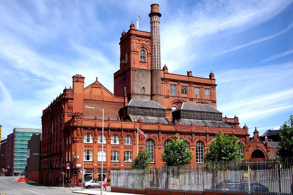 Competitive Socialising in Liverpool: Crazy Golf, Darts & Escape Rooms 1 The ornate red-brick Victorian Cain's Brewery building in Liverpool, with a tall square tower, a slim chimney and arched windows, under a blue sky