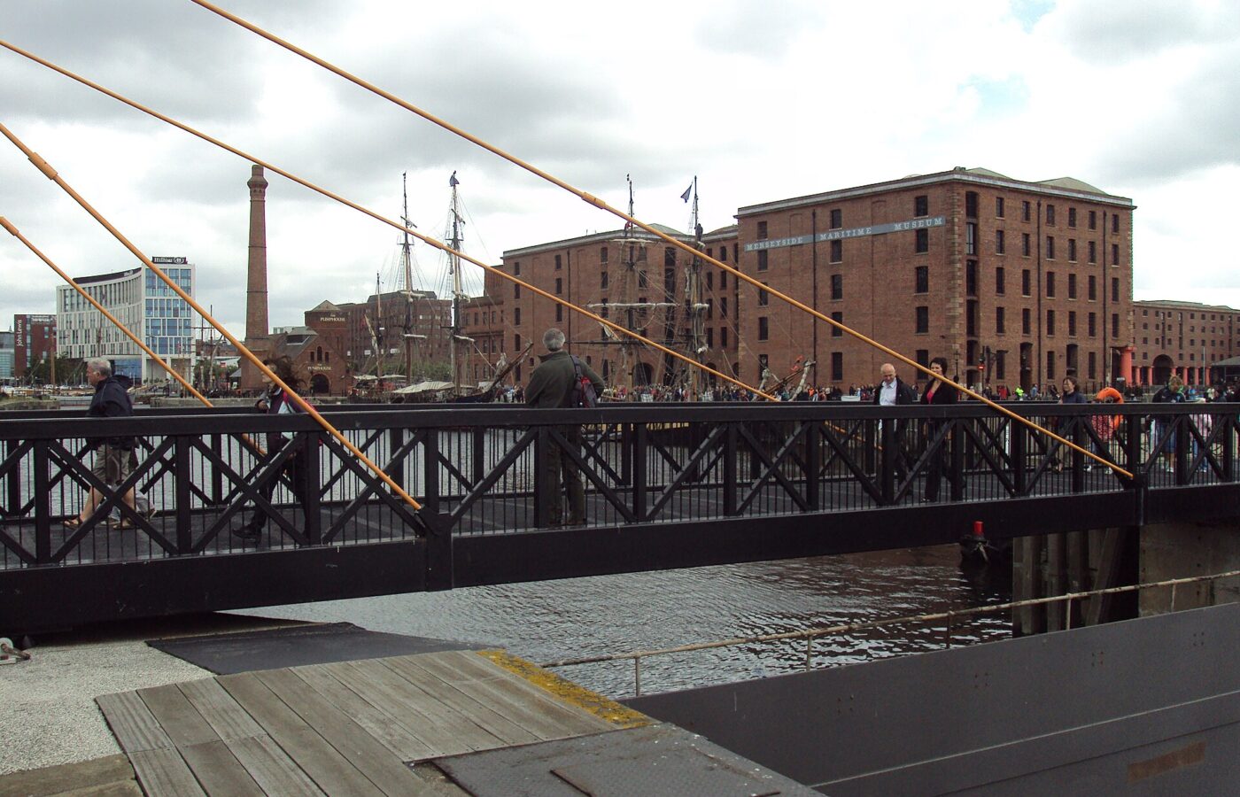 A level footbridge across Canning Dock in Liverpool with the Merseyside Maritime Museum warehouse behind it