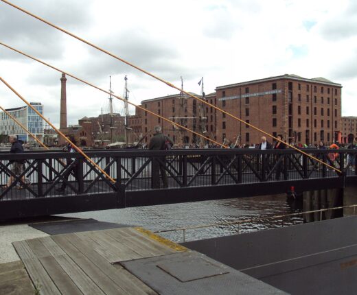 A level footbridge across Canning Dock in Liverpool with the Merseyside Maritime Museum warehouse behind it