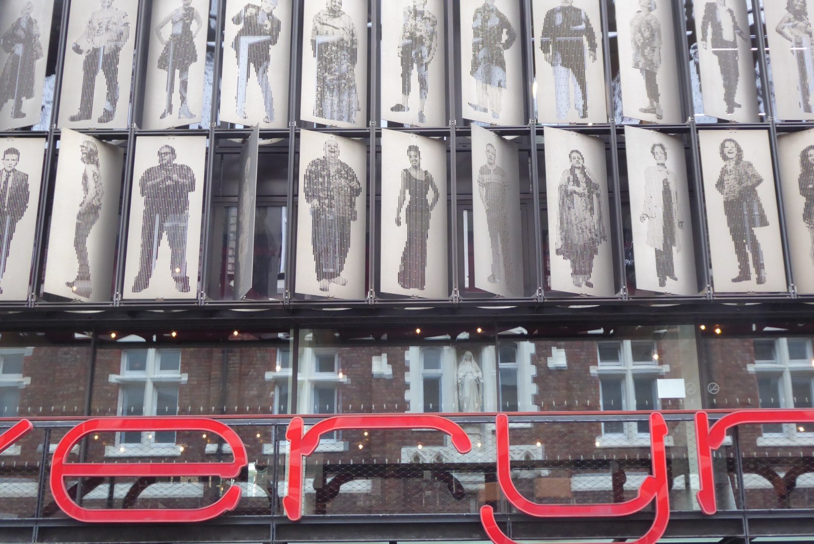 Liverpool Everyman & Playhouse: The City's Producing Theatres 2 Close-up of the Everyman Theatre's façade on Hope Street: rows of metal panels with life-size portraits of Liverpool people cut into them, above the red Everyman sign