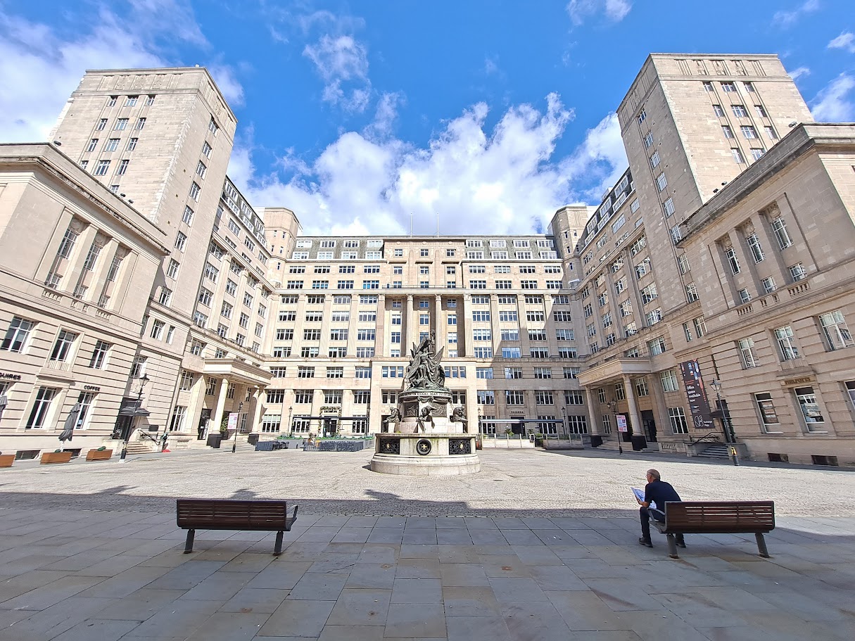 Liverpool on Screen: Blockbusters Filmed in the City 3 Exchange Flags square in Liverpool with the Nelson Monument at its centre and the tall stone Exchange Buildings around it under a blue sky