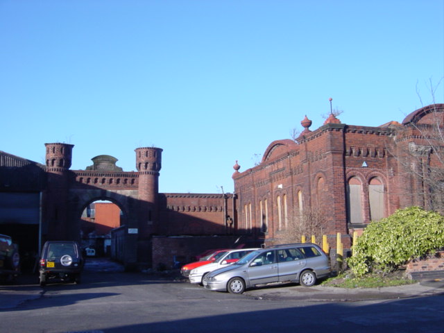 The red-brick castellated gateway and ornate buildings of the former Hartley's jam factory at Aintree, with cars parked in the yard