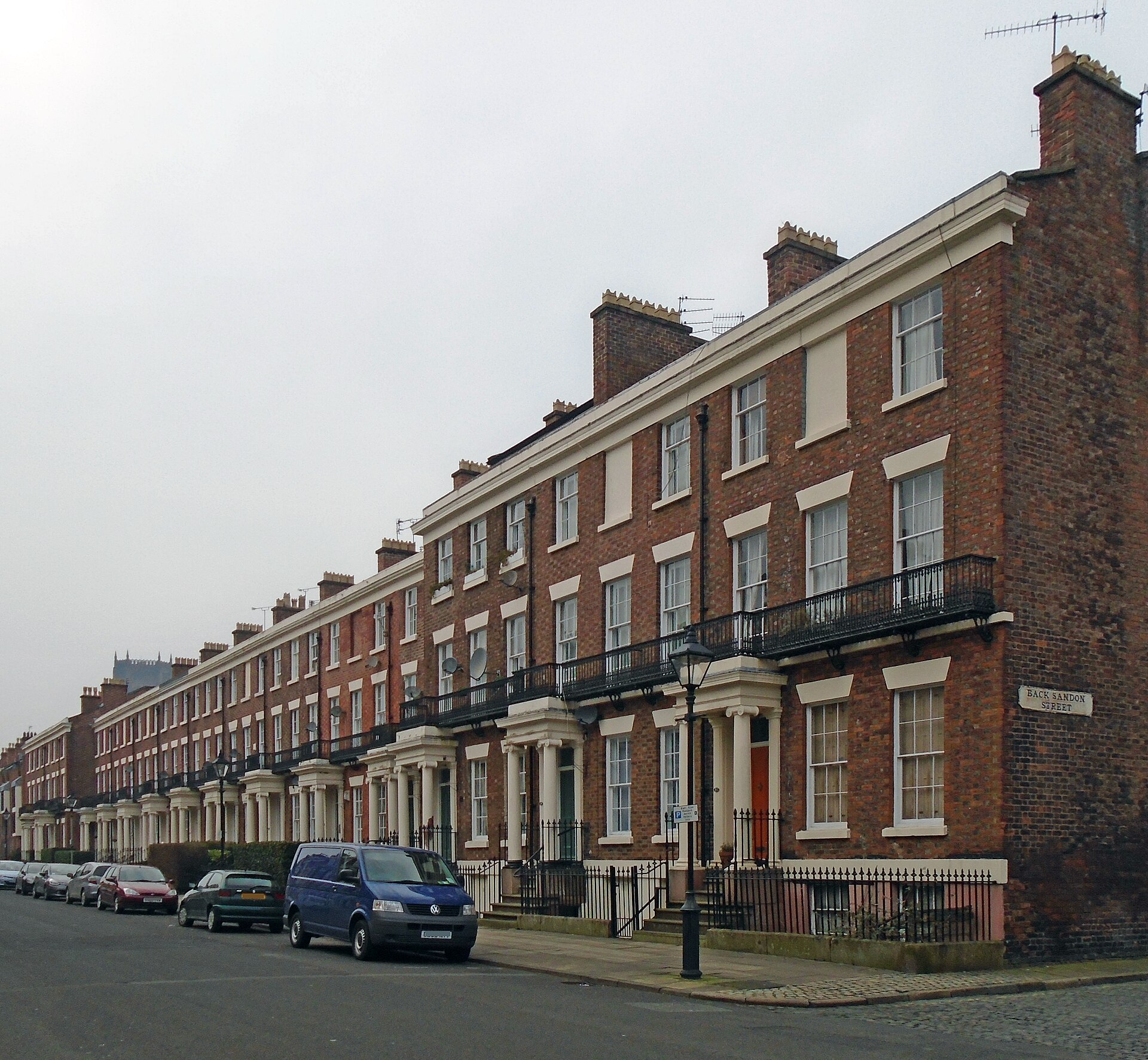 Most Instagrammable Places in Liverpool: Photo Spot Guide 2 A long Georgian brick terrace with iron balconies running along Huskisson Street in Liverpool, with cars parked along the kerb