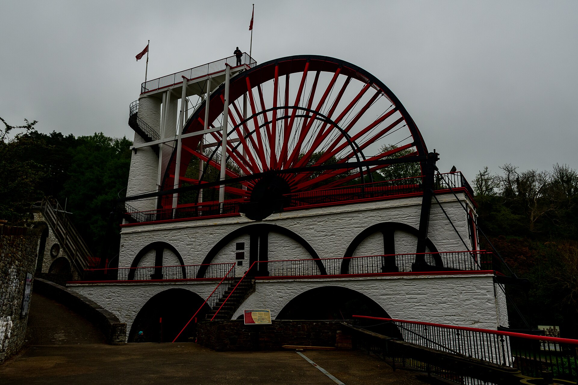 Isle of Man Ferry from Liverpool: Day Trips & Sailings 3 The Great Laxey Wheel on the Isle of Man, a giant red and black waterwheel on a white-painted stone tower with a viewing platform and flags on top