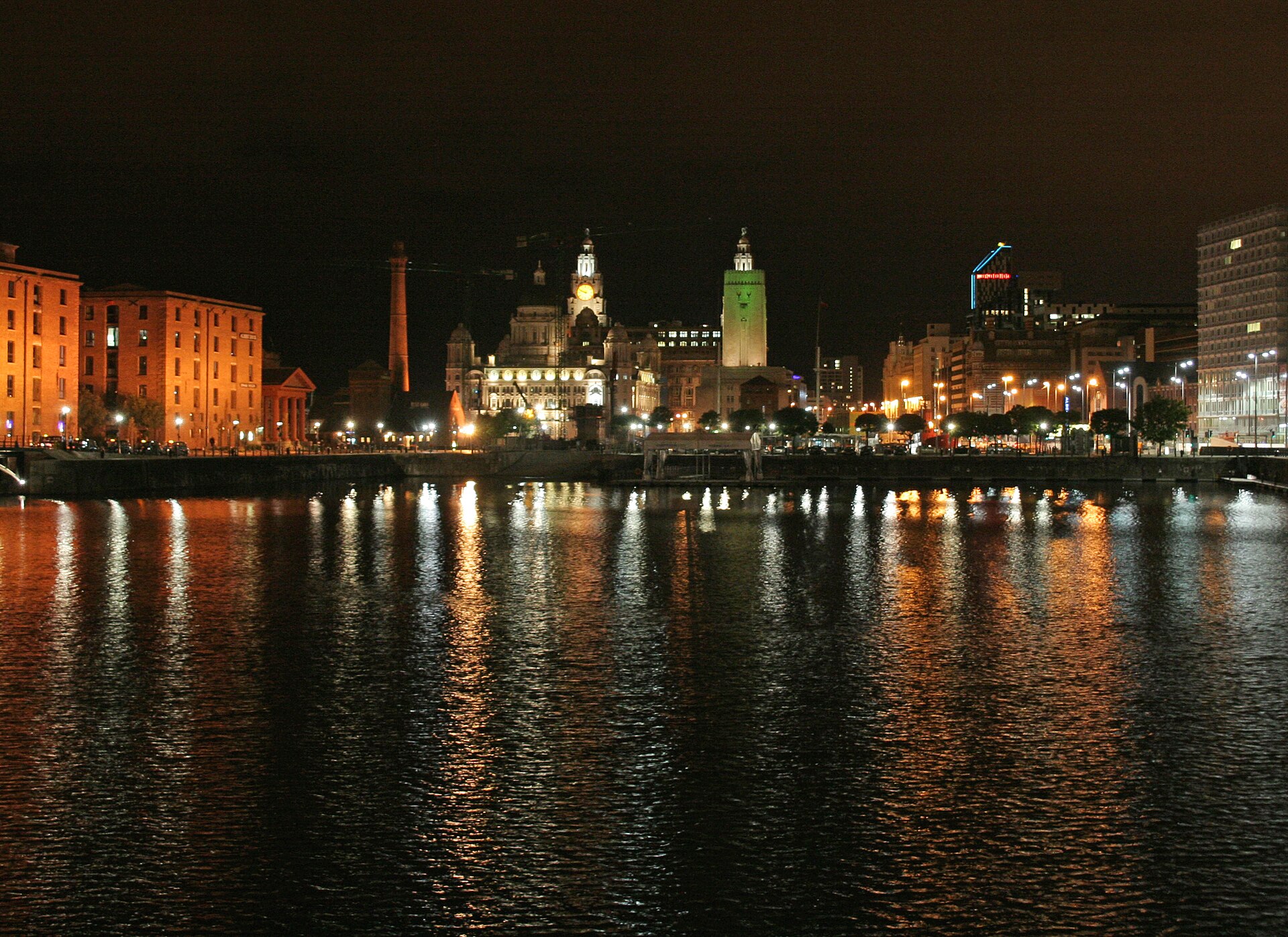Best Views in Liverpool: Viewpoints, Towers & Skyline Spots 3 Liverpool's Albert Dock and Pier Head lit up at night, with the Royal Liver Building reflected in the dark water of the dock