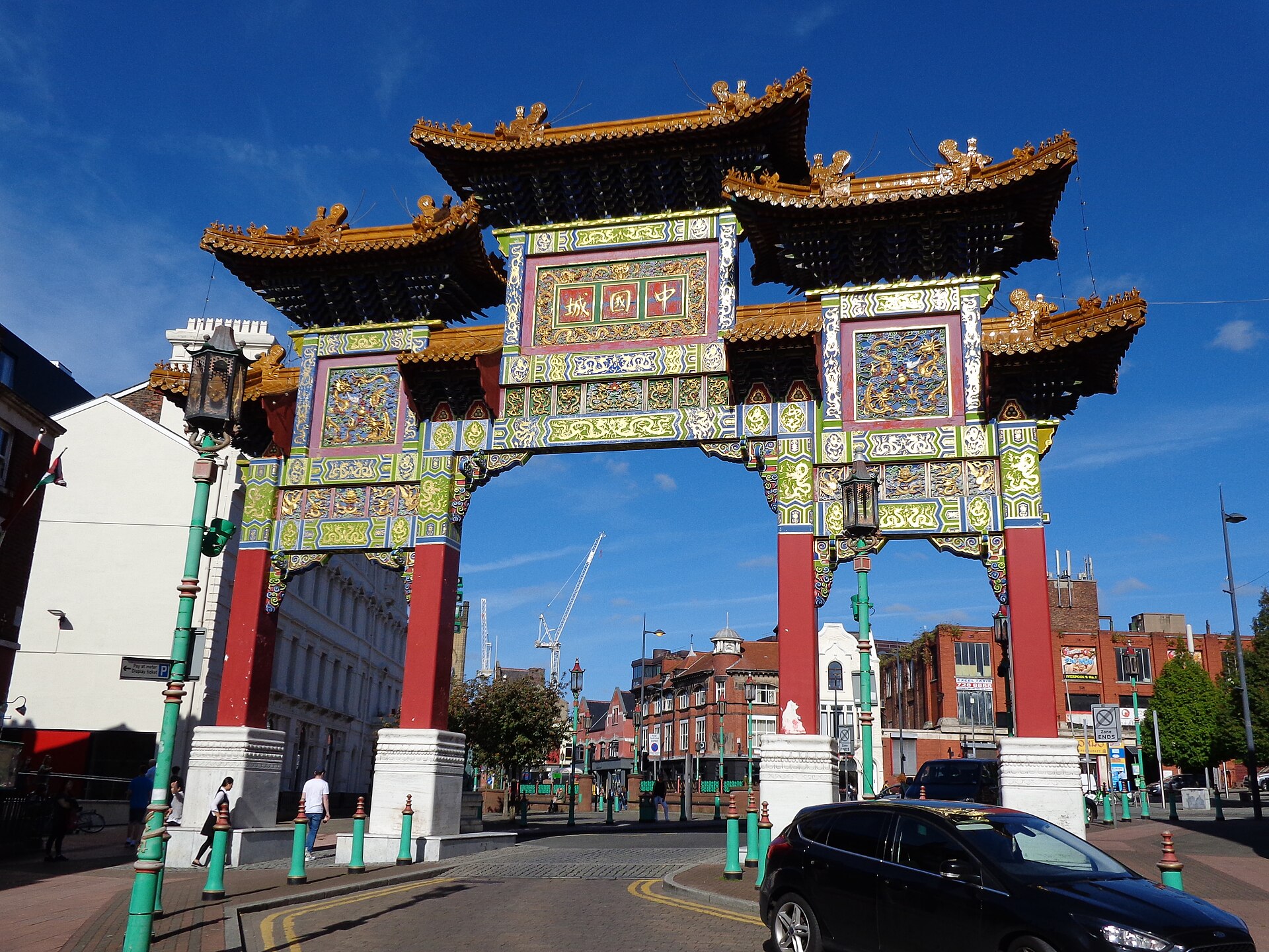 Most Instagrammable Places in Liverpool: Photo Spot Guide 4 The ornate Chinatown arch in Liverpool, with gold-tiled roofs, red pillars and panels of carved gold and green, under a blue sky