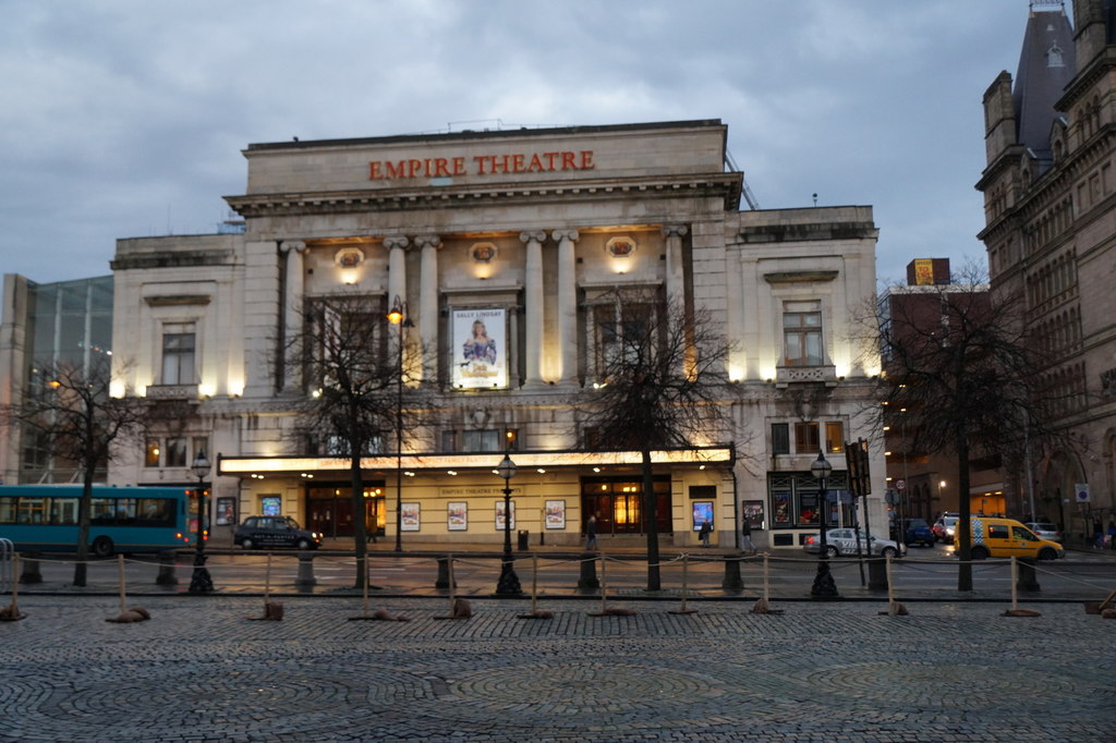 Liverpool Empire Theatre Guide: Seating, Shows & What to Know 1 The floodlit neoclassical front of the Empire Theatre on Lime Street, Liverpool, at dusk with a show poster between the columns
