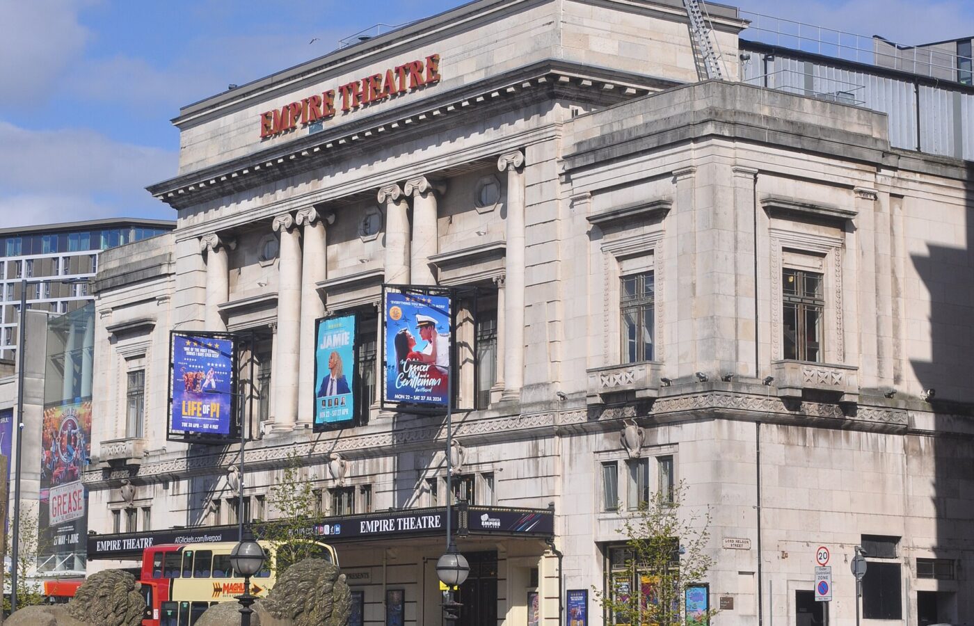 Liverpool Empire Theatre Guide: Seating, Shows & What to Know 4 The stone front of the Empire Theatre on Lime Street, Liverpool, with show banners between its columns, seen past the stone lions of St George's Plateau