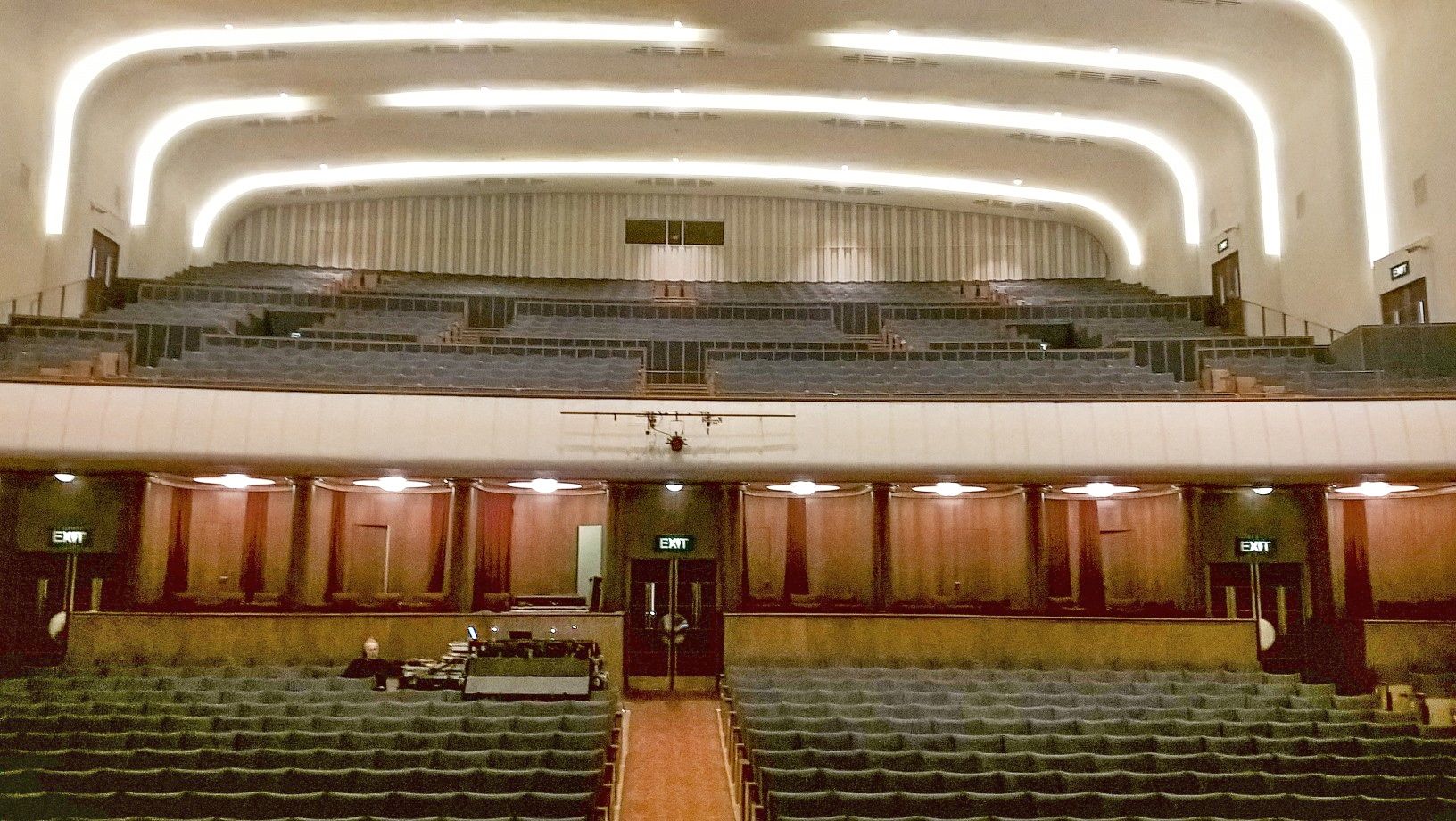 Liverpool Philharmonic Hall & the Royal Liverpool Philharmonic 1 The empty Art Deco auditorium of Liverpool Philharmonic Hall seen from the stage, with curved bands of light across the ceiling, a balcony of seats and wood-panelled walls behind the stalls