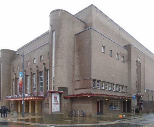 The brown-brick Art Deco exterior of Liverpool Philharmonic Hall on Hope Street, with rounded corner towers, tall narrow windows and the Liverpool Philharmonic name over the canopy