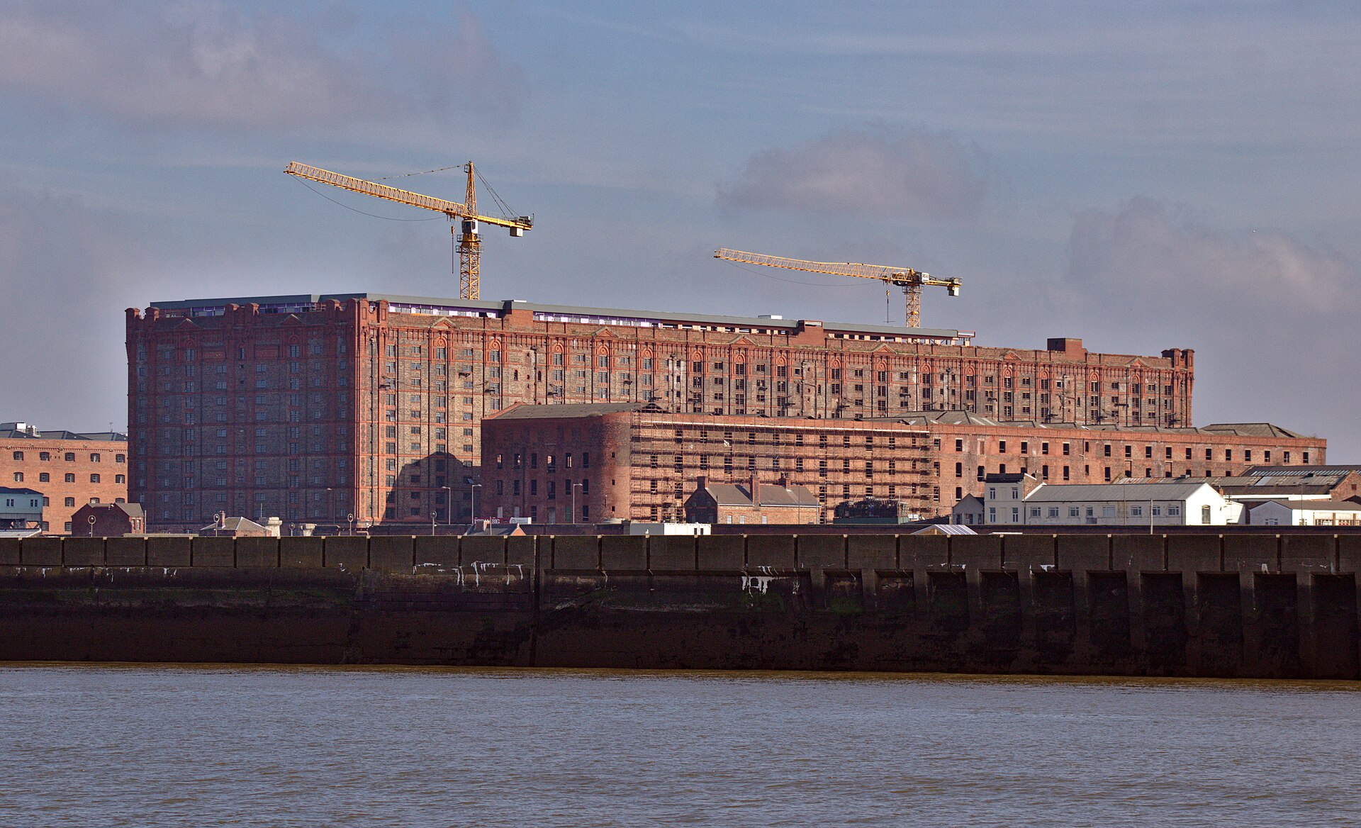 Liverpool Film & TV Locations: The Complete Guide 2 The vast red brick Stanley Dock Tobacco Warehouse in Liverpool seen from across the Mersey with construction cranes above it