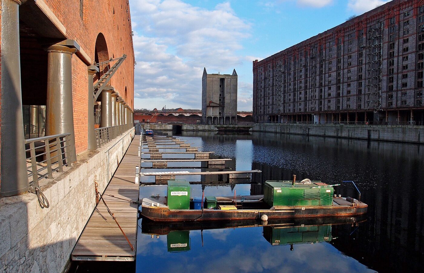 Stanley Dock in Liverpool with the vast Tobacco Warehouse on the right, the Titanic Hotel warehouse on the left and a work boat moored on still water