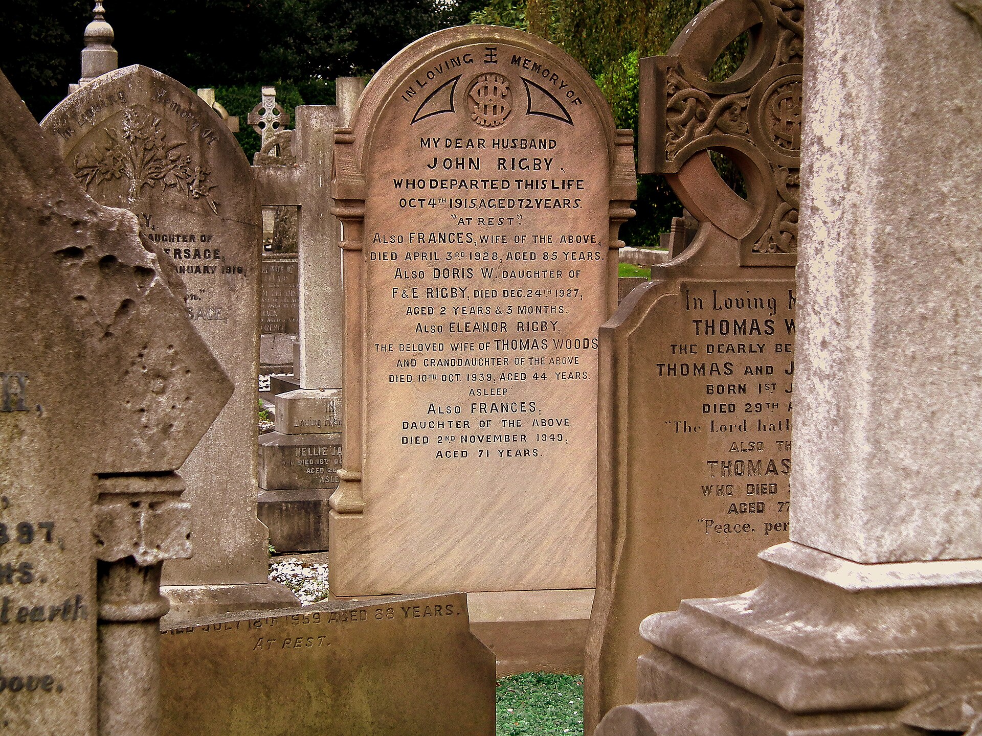 A weathered sandstone headstone in St Peter's churchyard, Woolton, carved with the names of the Rigby family including Eleanor Rigby, wife of Thomas Woods, who died on 10 October 1939 aged 44
