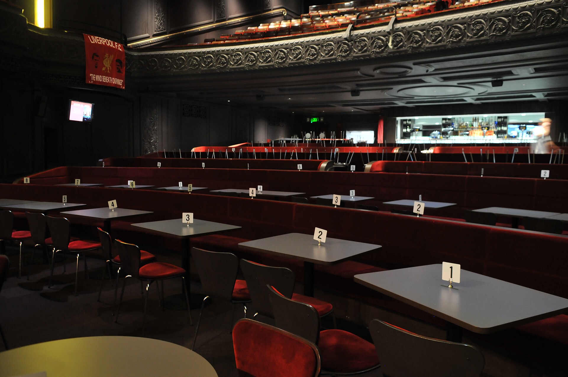 Royal Court Liverpool & Scouse Theatre: Comedies, Christmas & Dinner 1 The stalls of the Royal Court in Liverpool laid out cabaret style, with rows of numbered tables and red chairs facing the stage, and the balcony front above