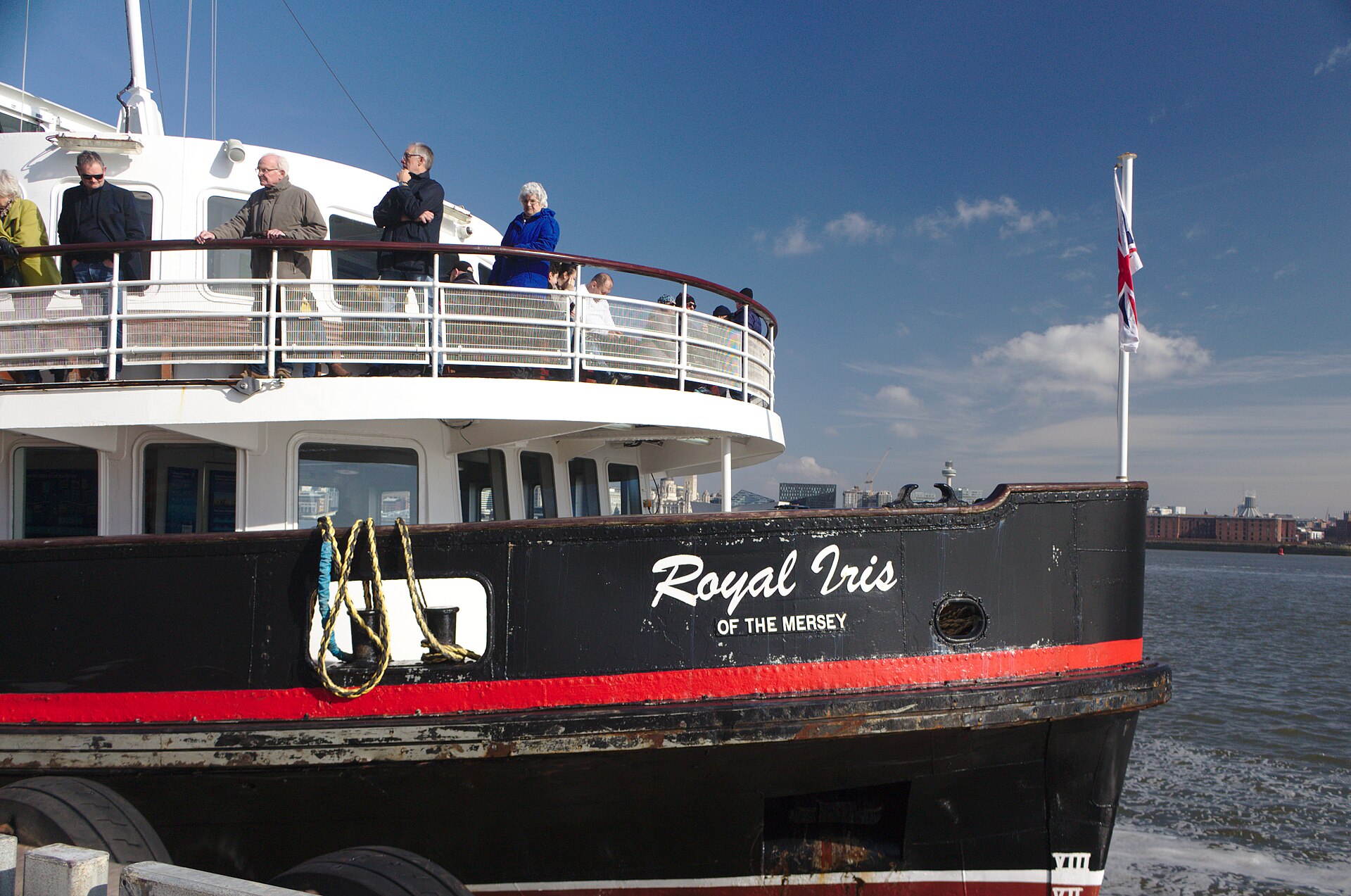 Birthday & Celebration Ideas in Liverpool for Groups 3 Passengers on the upper deck of the black, red and white ferry Royal Iris of the Mersey, with the Liverpool skyline across the river behind