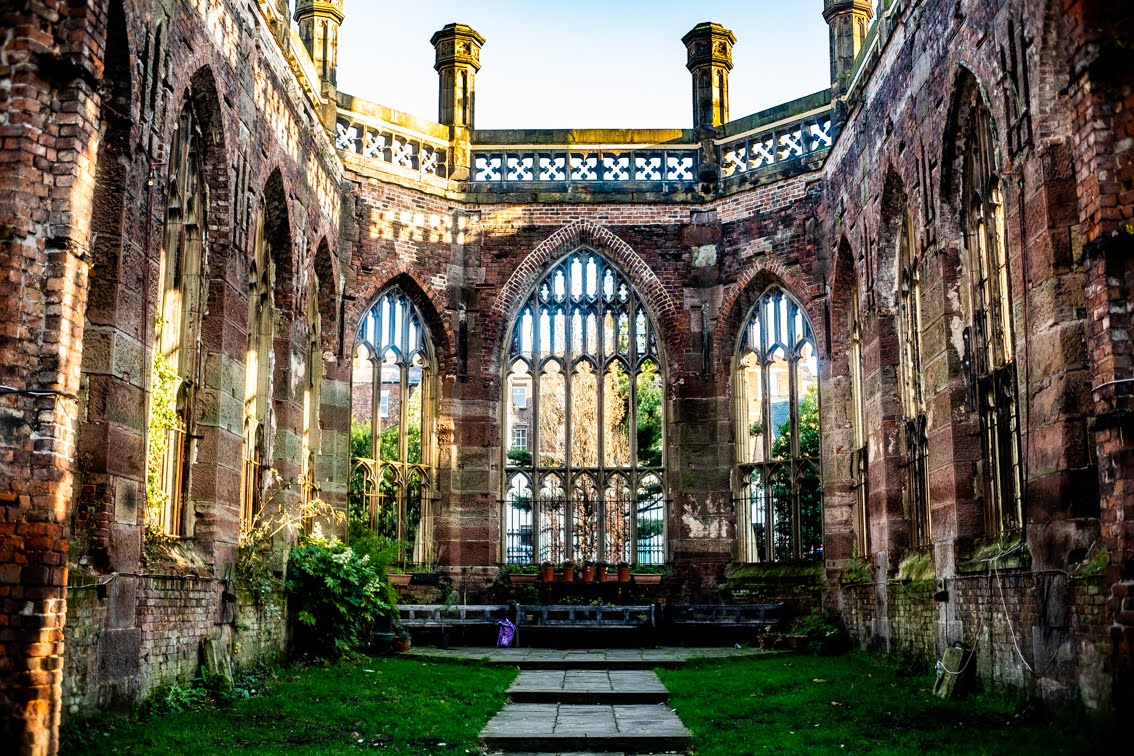 Most Instagrammable Places in Liverpool: Photo Spot Guide 6 Inside the roofless shell of St Luke's Bombed Out Church in Liverpool, with empty Gothic windows, red sandstone walls, a lawn and a paved path